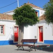 Casas com barra azul e porta vermelha e árvore