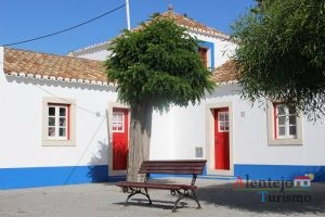 Casas com barra azul e porta vermelha e árvore