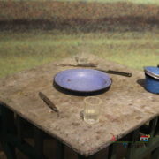 Prato azul, talheres e marmita sobre a mesa