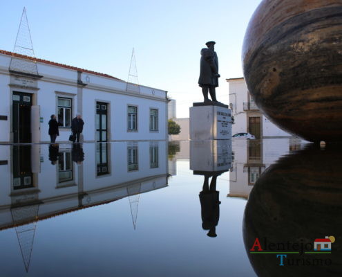 Reflexos na água de estátua, casa e esfera