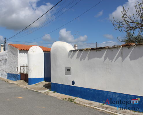Muro branco com barra azul e portão azul