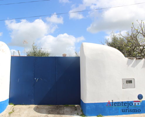 Aivados - Aldeia Comunitária - muro branco com barra azul e portão azul