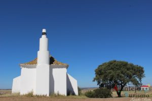 Igreja com marco geodésico e árvore.