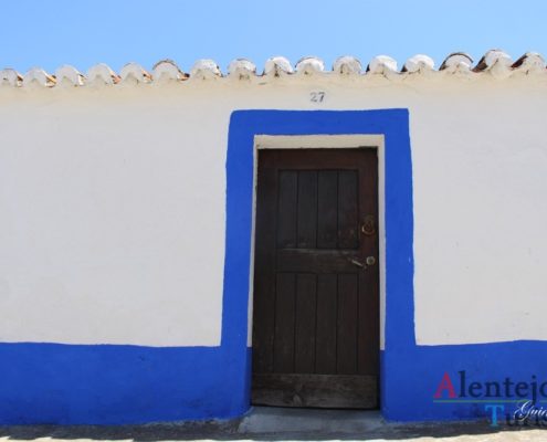 Casa com porta castanha e barras azuis.